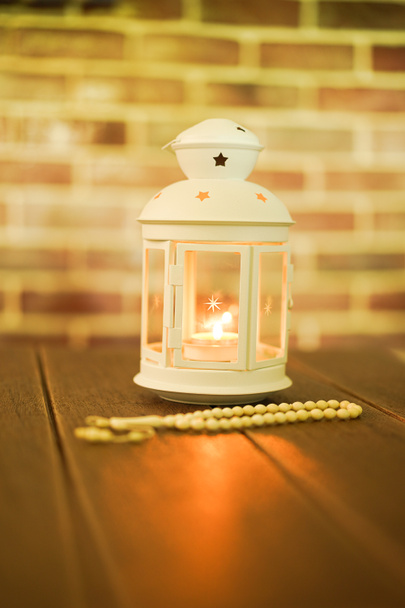 Islamic concept for Eid and Ramadhan. Traditional arabic lantern with Tasbih (Rosary Beads) on a wooden backgrounds, Selective Focus - Photo, Image