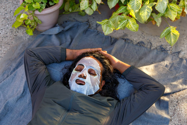 Indian bearded man relaxing with facial mask in a garden - Foto, Bild