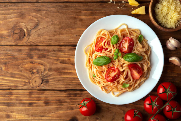 Spaghetti with tomatoes and cheese on a wooden background. Top view, copy space. - Foto, Bild