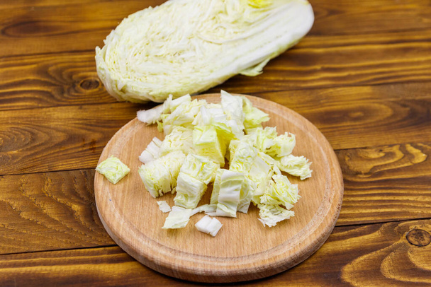 Chopped chinese cabbage on cutting board on wooden table - Фото, изображение