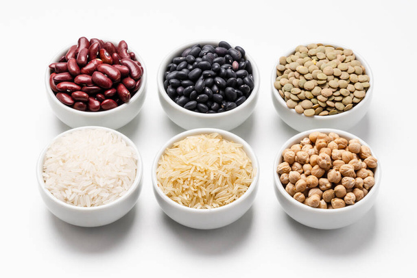 Neuvařená rýže a fazole. Mísa rýže Basmati obklopená jinými odrůdami zrn a luštěnin, jako jsou cizrna, červené fazole, zelená čočka, fazole černé želvy a jasmínová rýže. - Fotografie, Obrázek