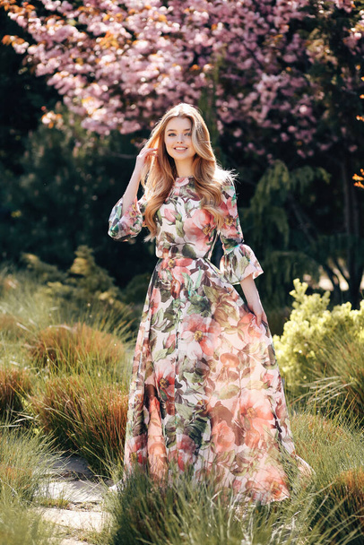 fashion outdoor photo of beautiful young woman with blond hair in luxurious dress with floral print  and accessories - Photo, image