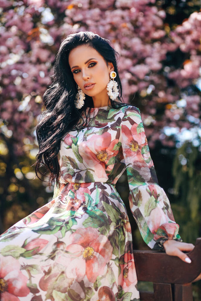 fashion outdoor photo of beautiful sensual woman with dark hair in luxurious dress with floral print  and accessories - Photo, Image
