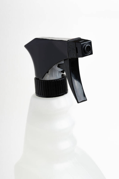  Um close-up da parte superior de uma garrafa de dispensador de plástico de spray líquido preto e branco em um fundo branco liso
. - Foto, Imagem