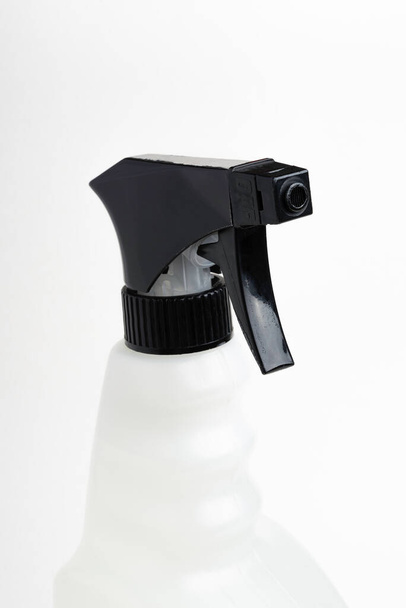  Um close-up da parte superior de uma garrafa de dispensador de plástico de spray líquido preto e branco em um fundo branco liso
. - Foto, Imagem