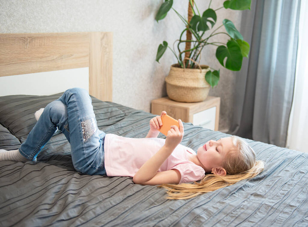 Šťastná roztomilá holčička hraje hry na smartphone doma - Fotografie, Obrázek