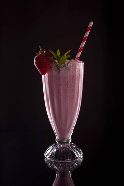 Koude verfrissende aardbeien ijs vers met cocktail tube op zwarte achtergrond - Foto, afbeelding