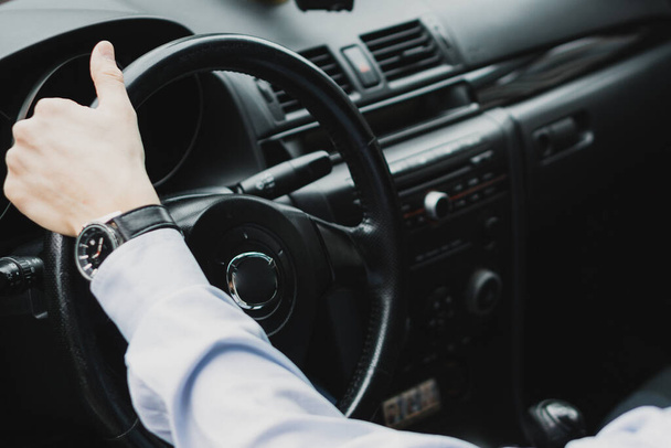     a man sitting behind the wheel of a car in a shirt on his watch       - Photo, image