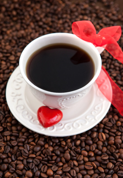 Taza blanca de café con corazón rojo en granos de café
 - Foto, Imagen