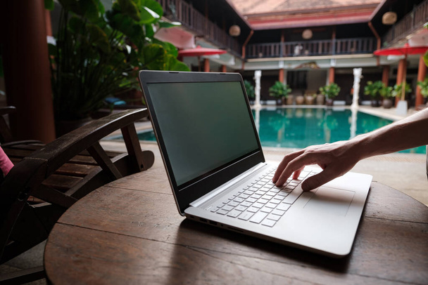 utazó blogger ül úszás medence írásban cikket fehér laptop. Szabadúszó távmunka koncepció. Önálló vállalkozó kódolva. Másolás tér, medence nézet háttér - Fotó, kép