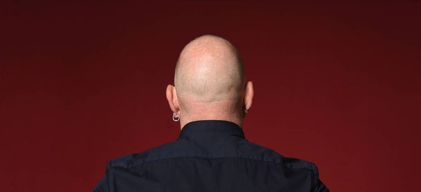 retrato de un hombre calvo, vista trasera, sobre fondo rojo
 - Foto, Imagen