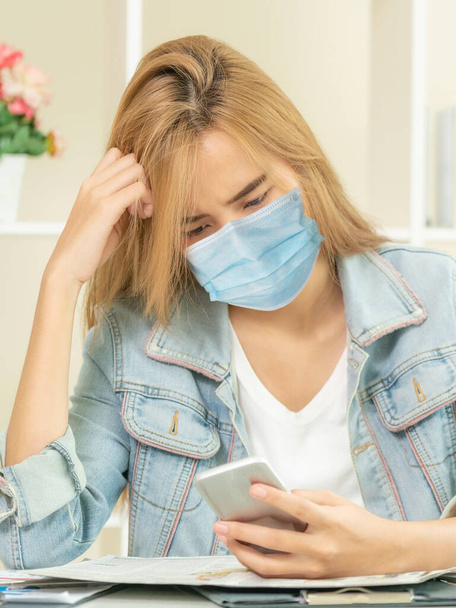 Quarantined woman working at home wearing face mask protect from Coronavirus. Concept of social distancing to stop spreading of Coronavirus Disease or COVID-19. - Foto, Imagem