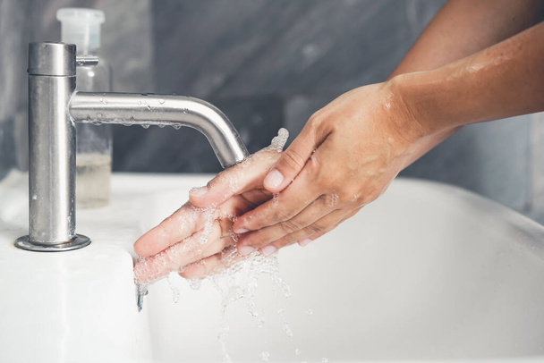 Hands washing for prevention of novel Coronavirus Disease 2019 or COVID-19 . People wash hands at bathroom sink to clean the virus infection. - Фото, зображення