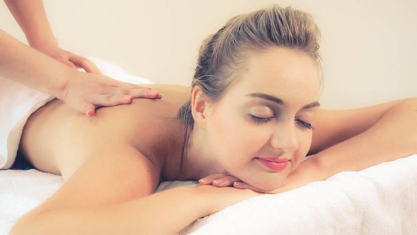 Zrelaksowana kobieta wraca do masażu w luksusowym spa z profesjonalnym masażystą. Koncepcja wellness, uzdrowienia i relaksu. - Zdjęcie, obraz