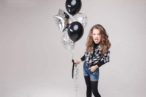 Cool pre-teen girl with rock sign. She is showing rock n roll or horn sign, gesturing at camera and pouting her lips with two air balloons. Stock studio portrait isolate on grey. - Photo, Image