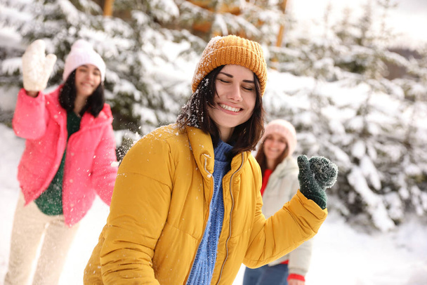Happy friends playing snowballs outdoors. Winter vacation - Foto, imagen