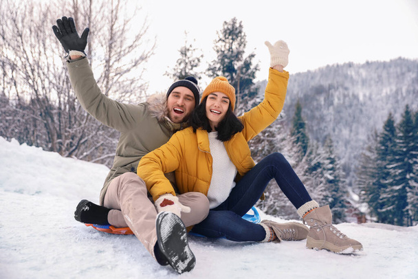 Happy couple sliding on snowy hill. Winter vacation - Foto, afbeelding