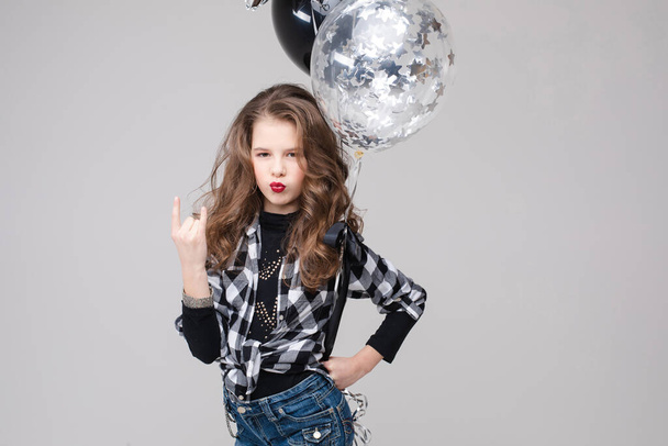 Cool pre-teen girl with rock sign. She is showing rock n roll or horn sign, gesturing at camera and pouting her lips with two air balloons. Stock studio portrait isolate on grey. - Fotografie, Obrázek