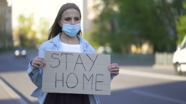  Jovem em protesto máscara médica com cartaz na rua da cidade. Equipa de pandemia de palavras
 - Filmagem, Vídeo