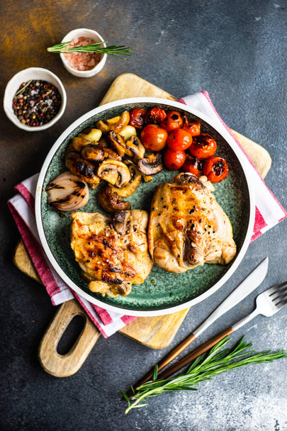 Grilled chicken meat and vegetables served on plate and spices on stone background with copy space - Photo, Image