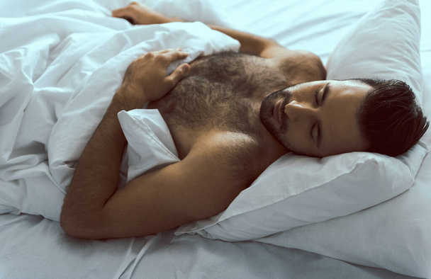 Happy attractive man sleeping in comfortable bed - Foto, Imagem