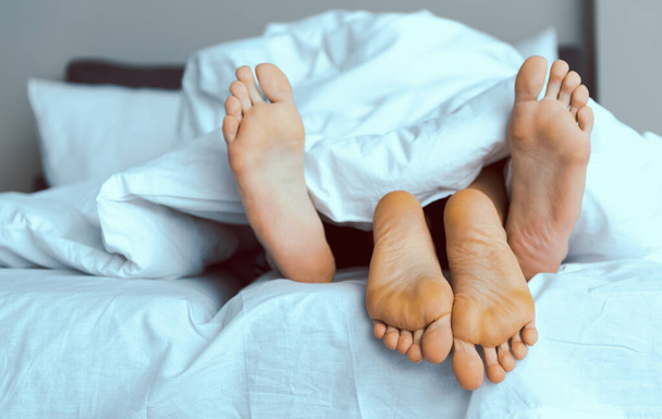 Loving couple cuddling under blanket in morning - Фото, зображення