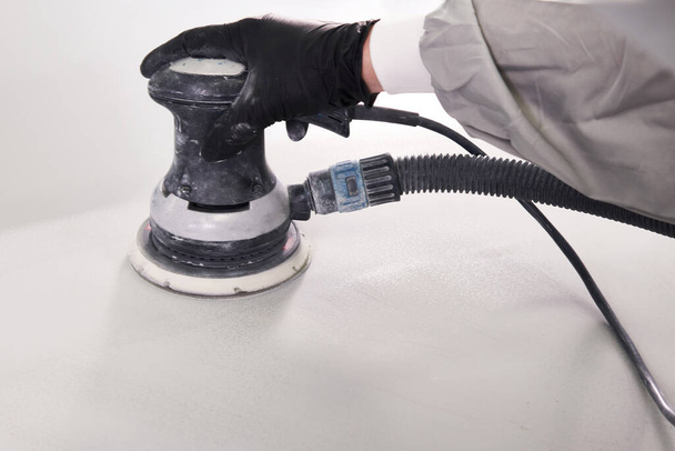 Auto mechanic buffing and polishing car in auto repair shop with orbital polisher, basic layer cleaning - Foto, imagen