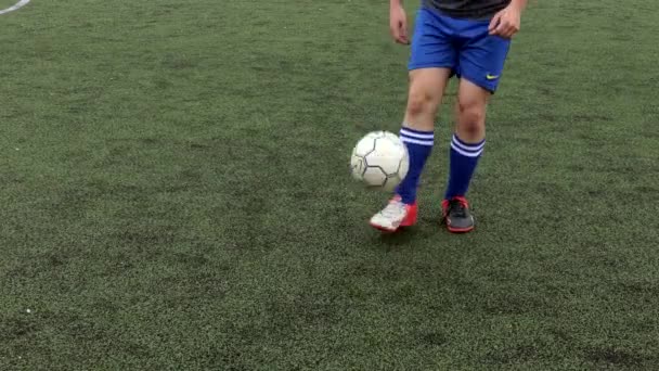 Ukrajina, Kyjev- Prosinec 19, 2019: Fotbalista dělat triky, aby se zabránilo obránce, kapání fotbalový míč na zelené trávě. - Záběry, video