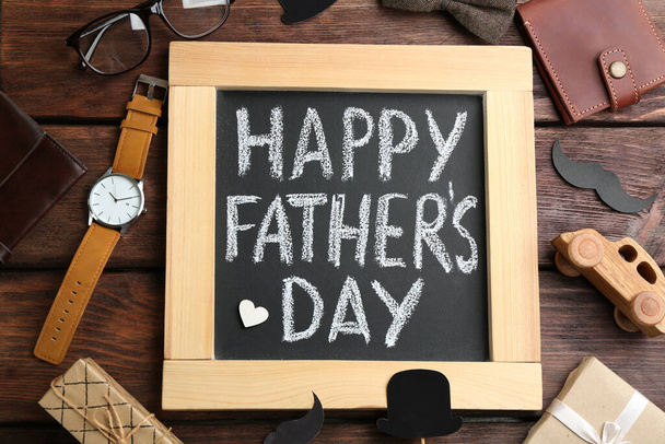 Schoolbord met woorden HAPPY FATHER 'S DAY en mannelijke accessoires op houten ondergrond, plat gelegd - Foto, afbeelding