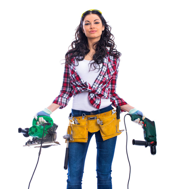 Project Satisfaction. Beautiful sexy brunette woman with a circular saw and perforator, isolated on white background - Fotografie, Obrázek