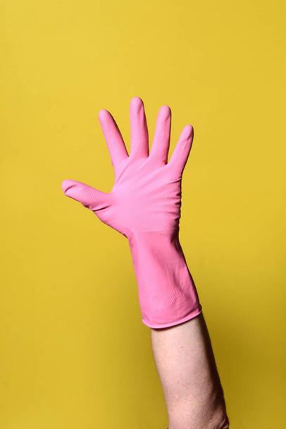 mano con guante sobre fondo amarillo
 - Foto, Imagen
