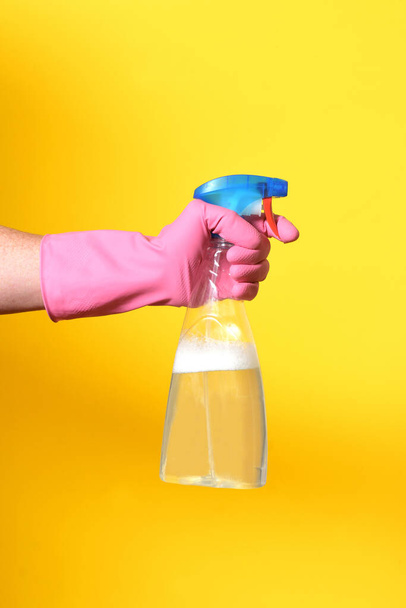hand with spray bottle on yellow background - Fotó, kép