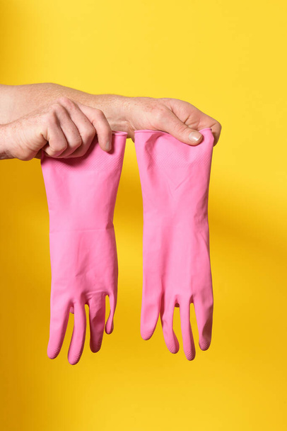 hands holding gloves on yellow background - Foto, Imagen