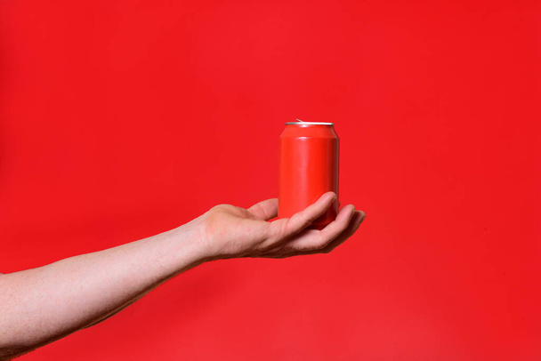 man holding a can on red background - Foto, Bild