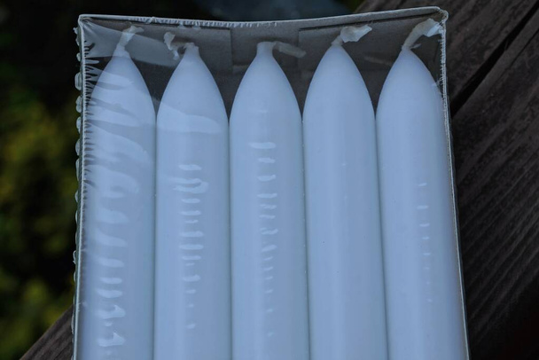 une rangée de bougies blanches en paraffine dans un emballage plastique transparent
 - Photo, image