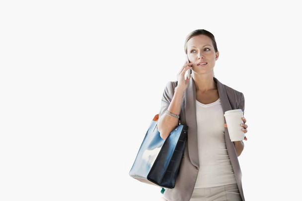 Portrait of young attractive businesswoman talking on smartphone and holding cup of coffee isolated on white - Φωτογραφία, εικόνα