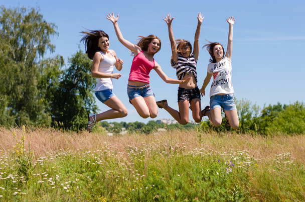 τέσσερις φίλοι ευτυχισμένος έφηβος κορίτσια υψηλά άλματα μπλε ουρανό - Φωτογραφία, εικόνα