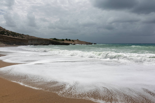 Dramatische regenachtige lucht en stormachtige golven op een zandstrand van de Egeïsche Zee in Rhodos. - Foto, afbeelding