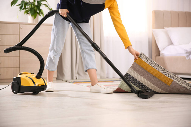 Young woman using vacuum cleaner at home, closeup - Фото, изображение