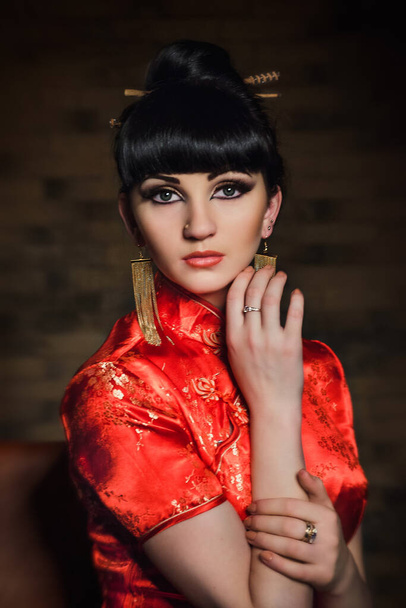 girl in a red Japanese silk dress qipao in a dark atmospheric room - Photo, Image