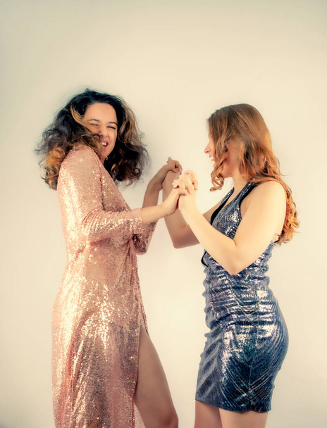 Portrait of best friends, pretty girls having fun, indoor party and crazy looking, laughing.Wearing shiny dresses.Isolate.Happy Teenage Girls Dancing. Beauty Teenagers Having Fun together. Girlfriends - Photo, image