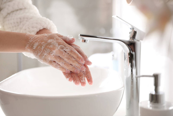 Woman washing hands with soap over sink in bathroom, closeup - Fotoğraf, Görsel