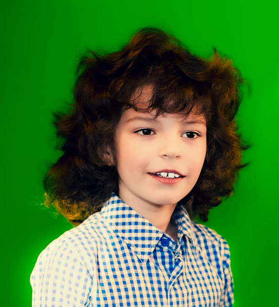 Little caucasian brunette boy close up portrait on green wall background - Photo, Image