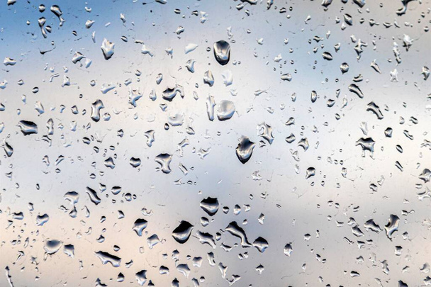 Gotas de lluvia en el vidrio, fondo del cielo azul con nubes de lluvia
. - Foto, Imagen
