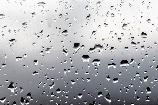 Gotas de lluvia en el vidrio, fondo del cielo azul con nubes de lluvia
. - Foto, Imagen