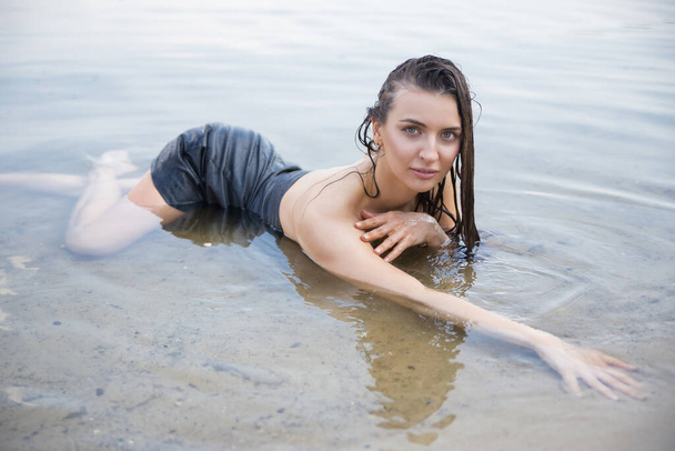 Donna con i capelli bagnati giace braccia distese sulla spiaggia. - Foto, immagini