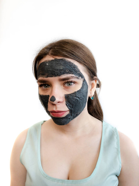 Mascarilla de barro purificadora tratamiento facial de barro para mujeres. Máscara cosmética de arcilla negra para la cara. Máscara cosmética en el modelo aislado sobre fondo blanco
. - Foto, imagen
