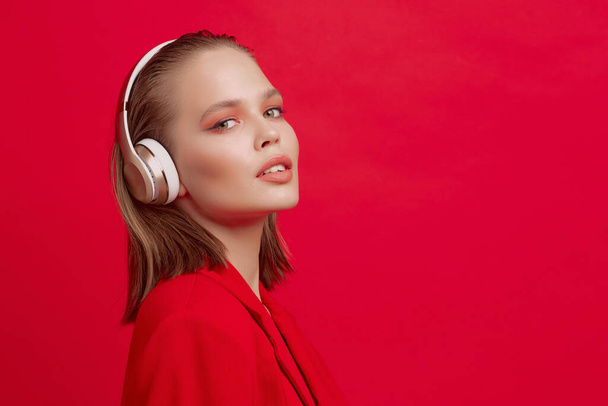 A beautiful young girl in wireless headphones listens to song with a good mood. bright colorful music poster. - Foto, imagen