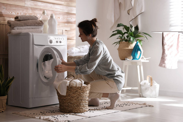 Young woman taking laundry out of washing machine at home - Foto, Imagem