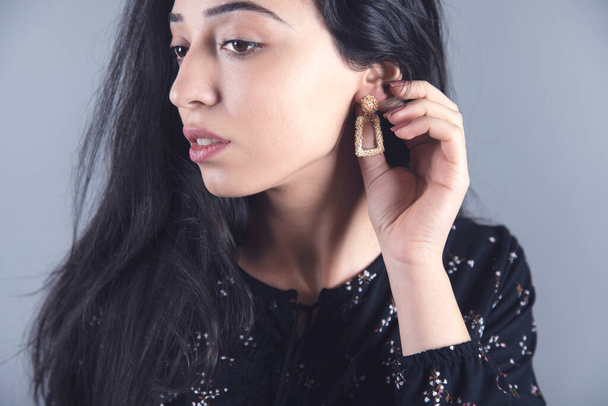 woman hand elegant earring on grey background - Foto, afbeelding